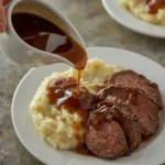 Glossy beef gravy poured over roast beef and mashed potatoes