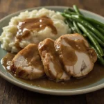 Slices of slow cooker turkey breast with gravy, mashed potatoes and green beans
